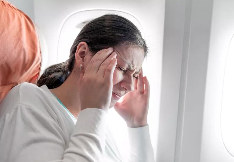 Woman with migraine headache on airplane