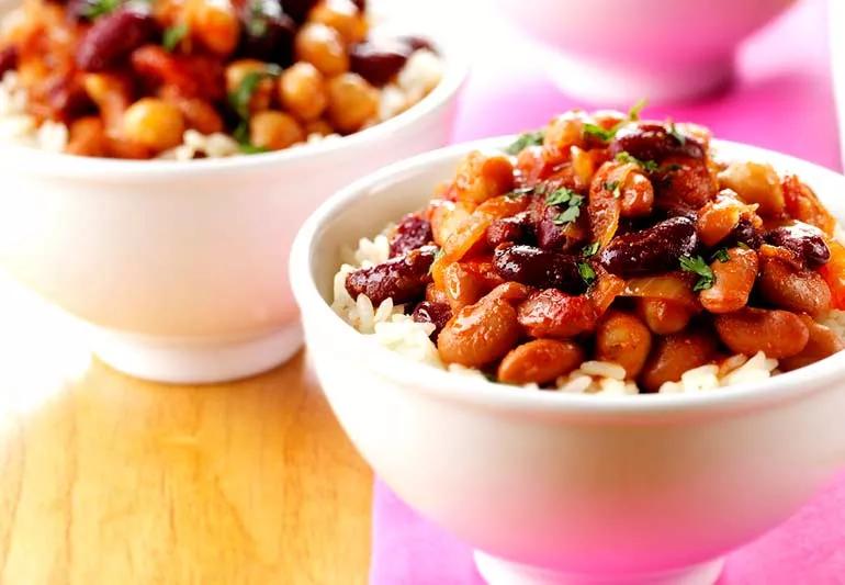 Small white bowls filled with rice and chili on colorful background.