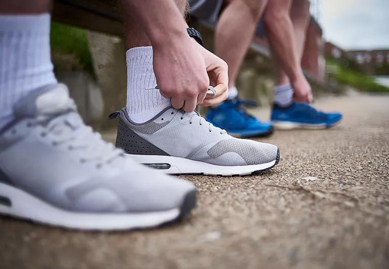 Two runners lace up their shoes before hitting the track.