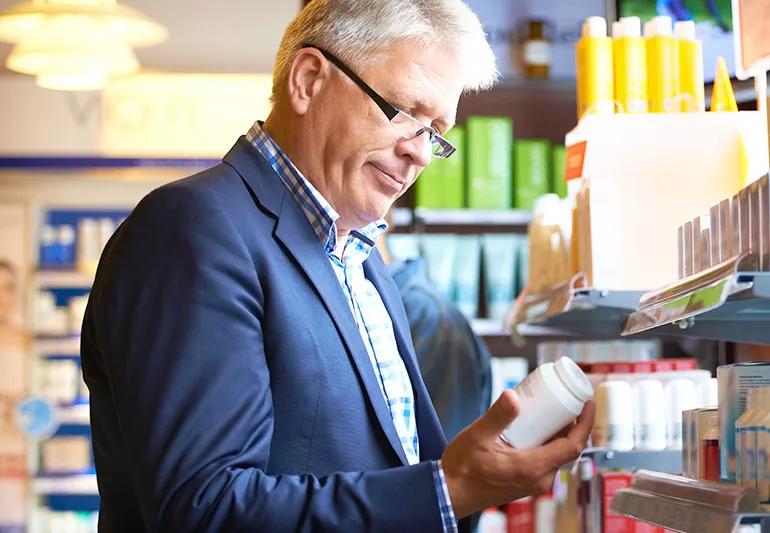 Elderly person shops for supplement at drug store.