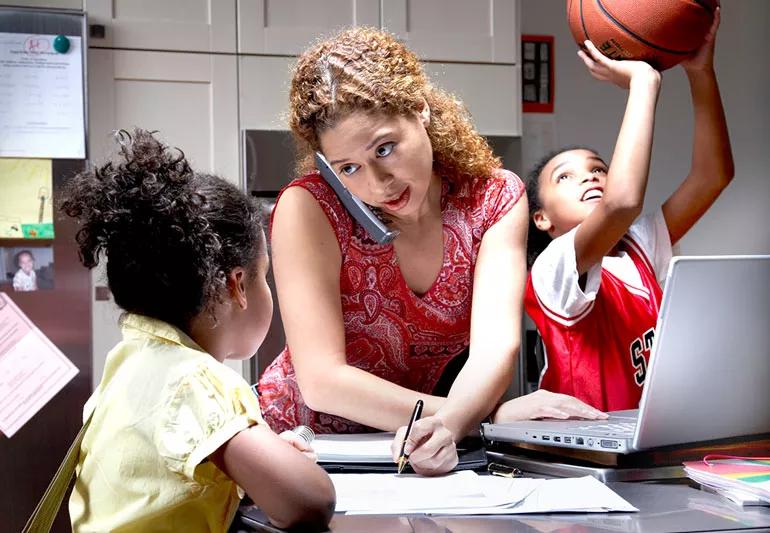 mother multitasking while 2 daughters distract her