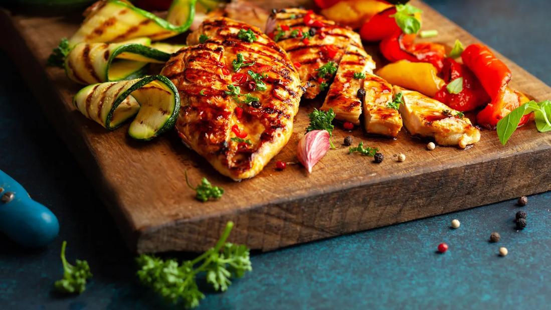 Grilled chicken with summer vegetables on cutting board