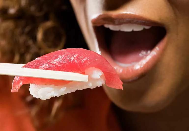 Person eating raw fish.