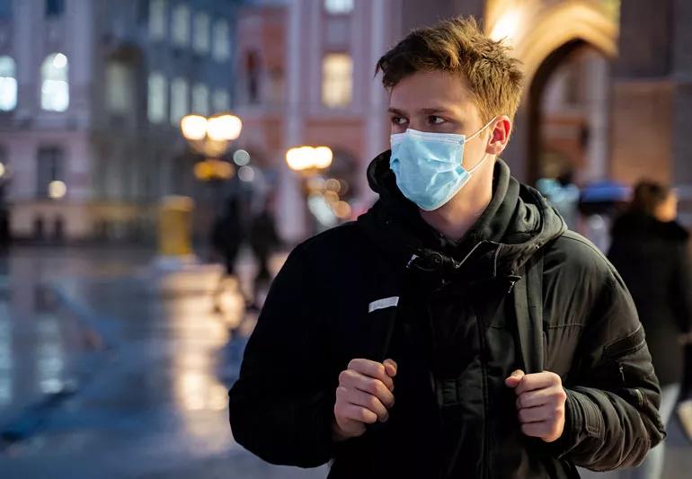 young man on street at night with mask on