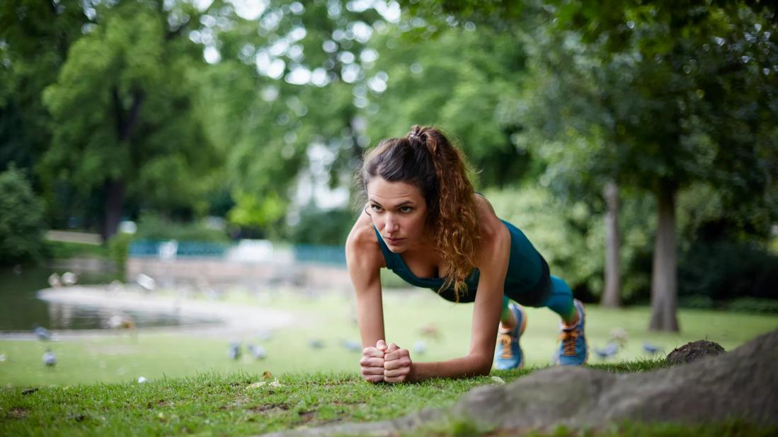 Person doing a plank in a park under a tree