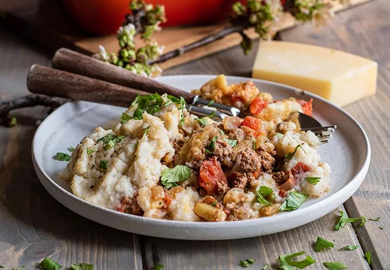 A plate of shepherd's pie with mashed potatoes, lamb and vegetables