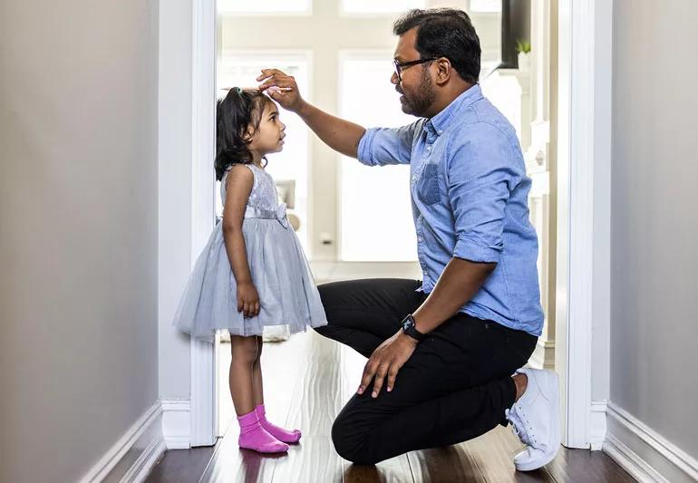 Parent measures child's growth by marking the wall they stand against.