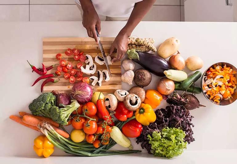 person cutting vegetables and fruit on kitchen counter top