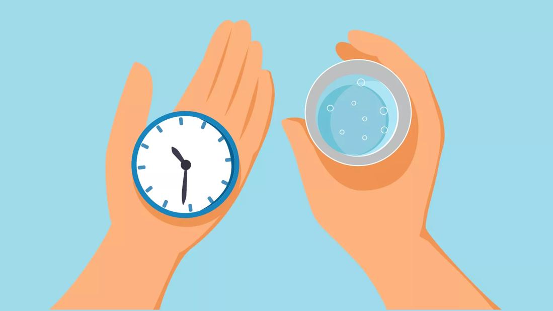two hands holding a stopwatch and a cup of water