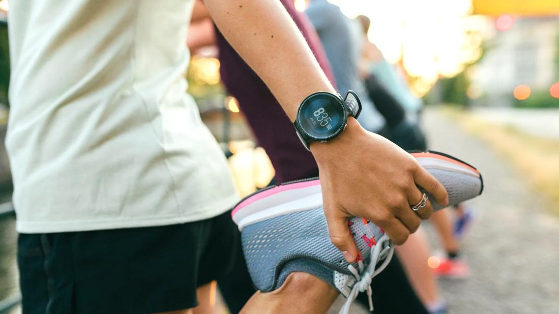 Person stretching leg in prep for a run, wearing a smartwatch on wrist