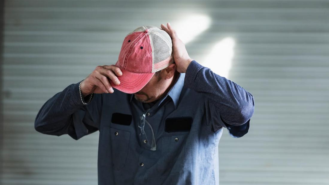 Man putting on a red ball cap hat