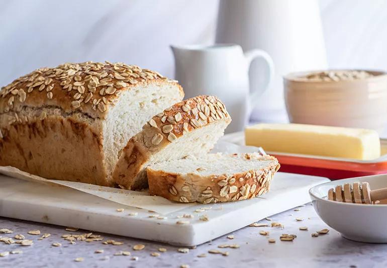 A loaf of honey oat bread with two slices cut