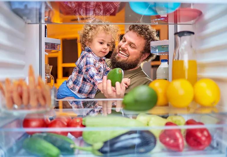 Man and son find healthy snack in fridge