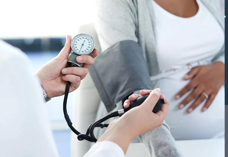Doctor taking blood pressure of pregnant woman