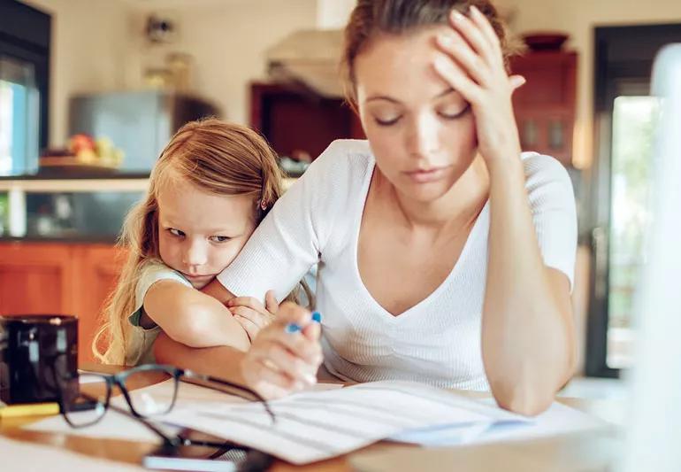 Child clinging onto mother while she is working