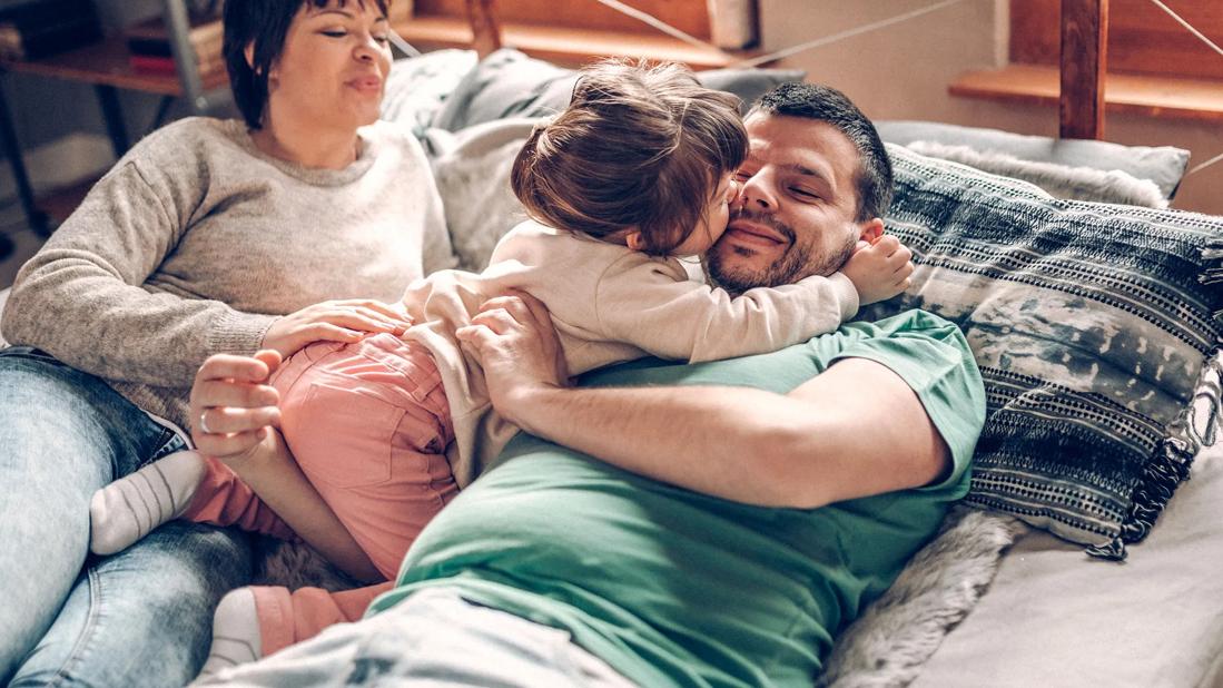 Partners lying on bed playing with their toddler