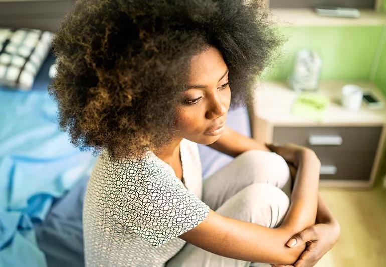 pensive woman sitting on bed