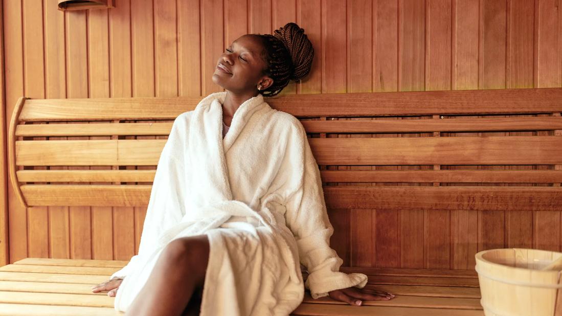 Smiling person in a robe sitting in a sauna