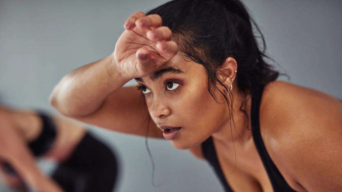 Female sweating and wiping brow during workout