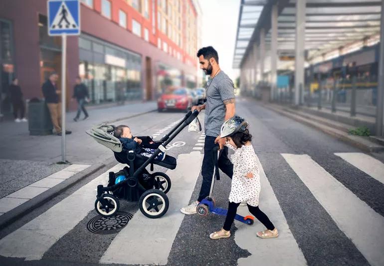 Father on walk with baby in stroller and young daughter