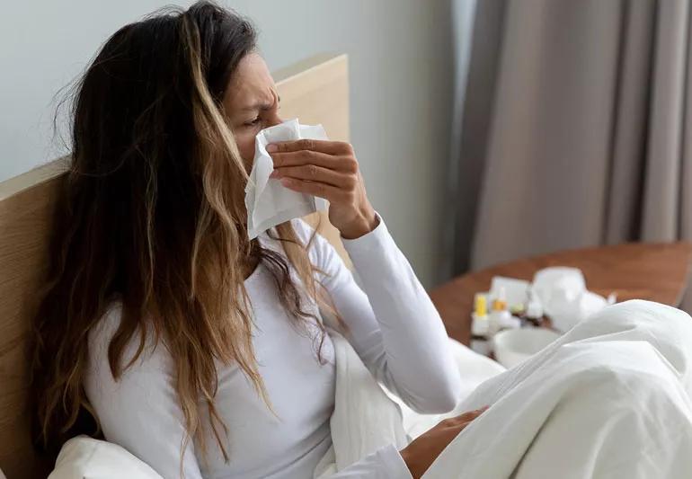 woman sick in bed and sneezing