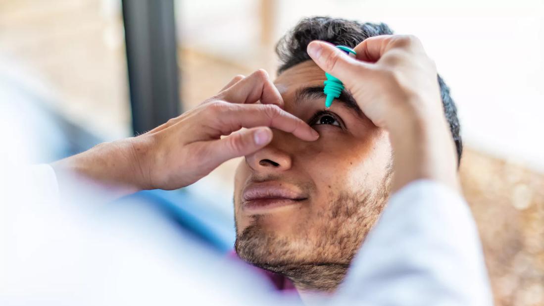 Adult receiving eye drops from a healthcare provider