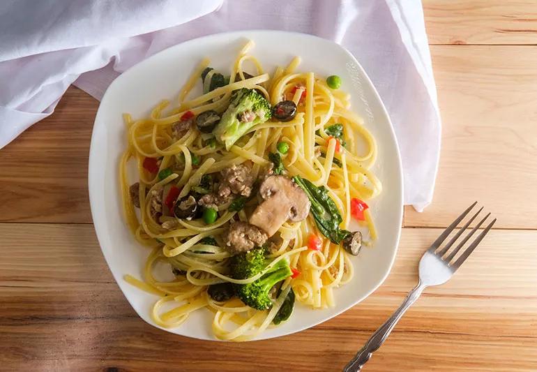 A plate of spaghetti noodles with broccoli and mushrooms