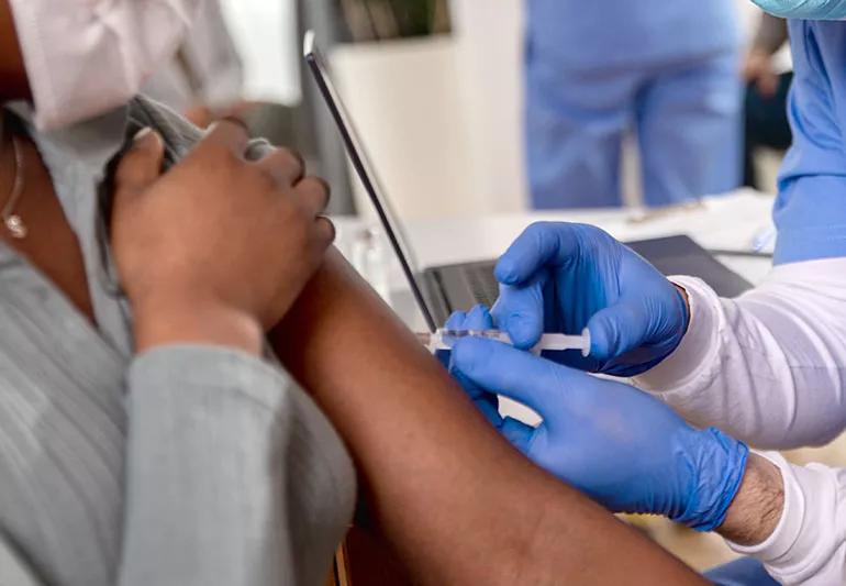 Person is getting a flu shot at a clinic by a nurse.