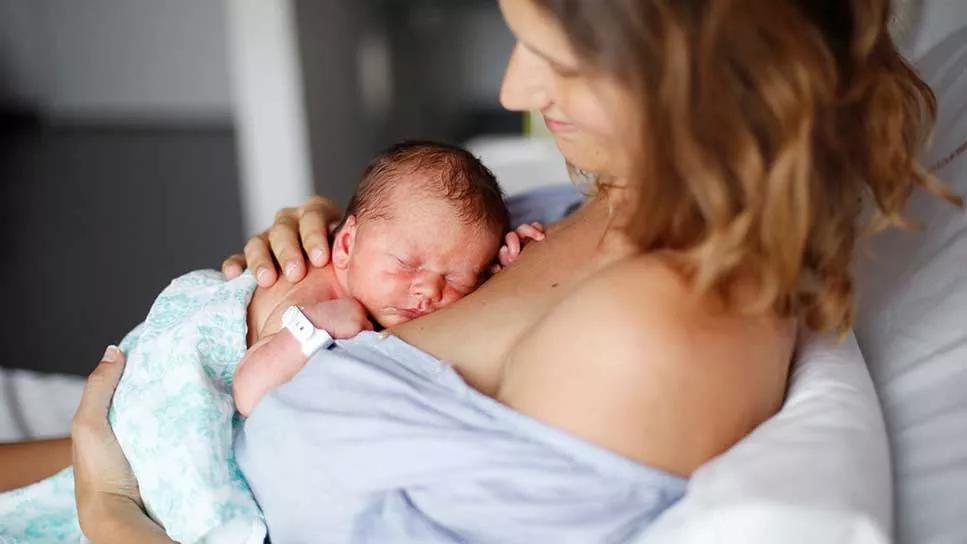 mother with newborn on chest in hospital bed