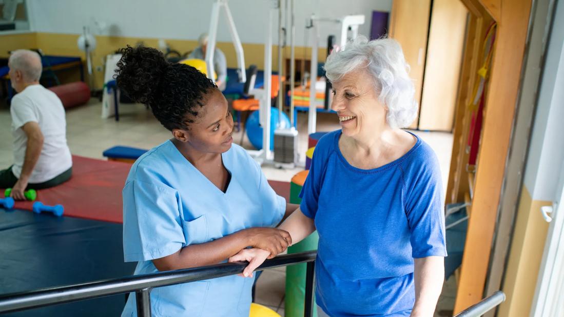 Physical therapist helping person with walking in therapy gym