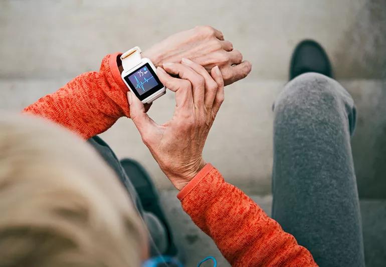 elderly woman checking her heart rate on a smart watch while exercising