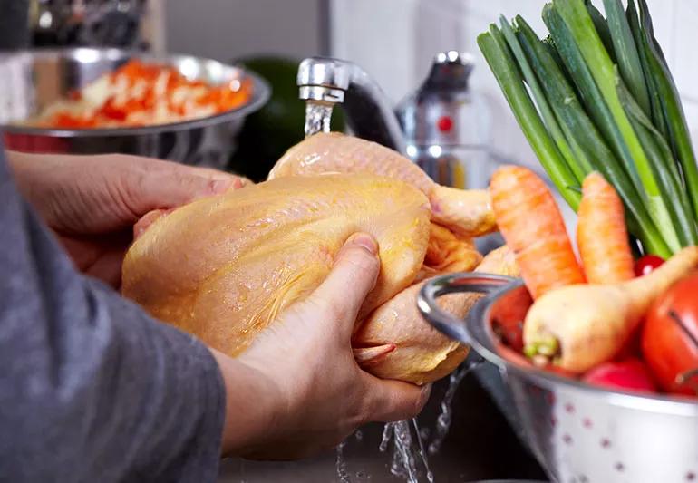 man washing chicken in the sink