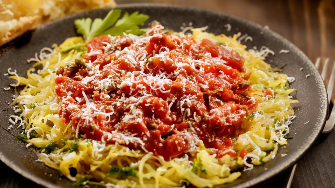 Wide bowl of spaghetti squash with tomato sauce and cheese