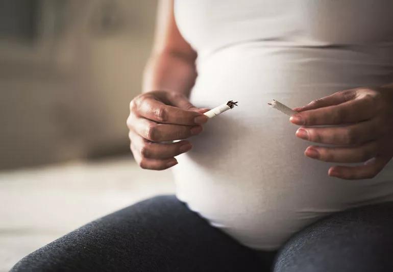 Pregnanct person breaking cigarette