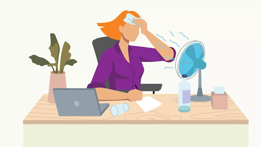 person at desk sweating and using a desk fan