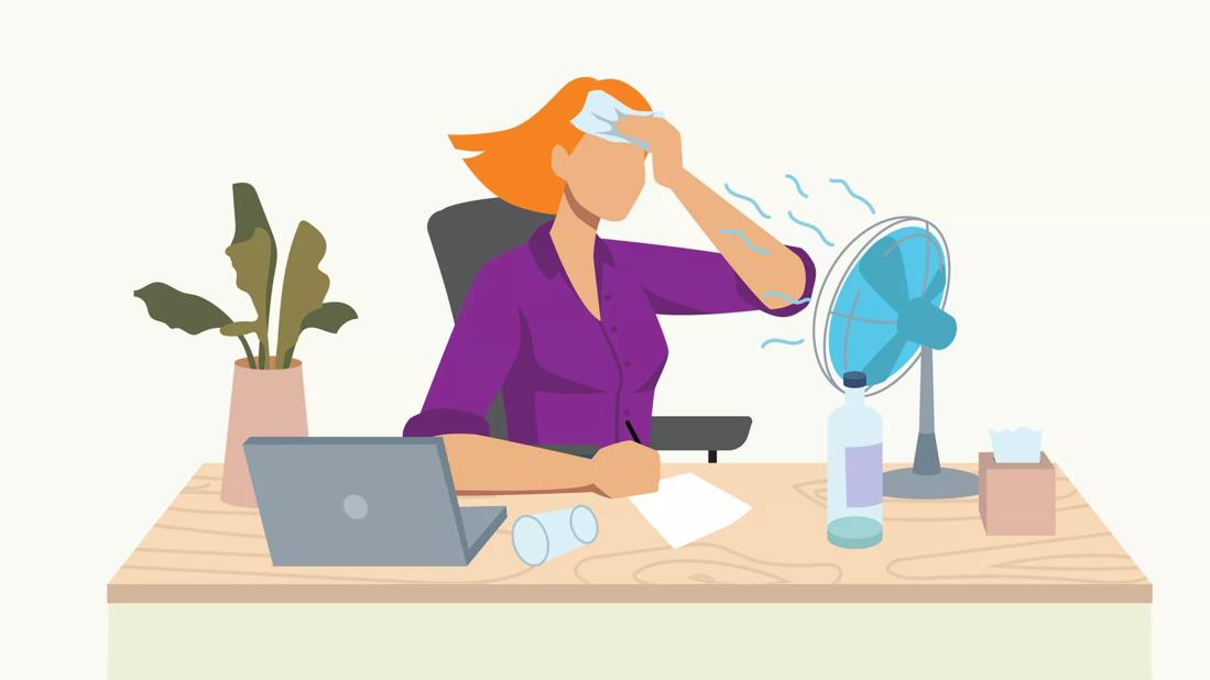 person at desk sweating and using a desk fan