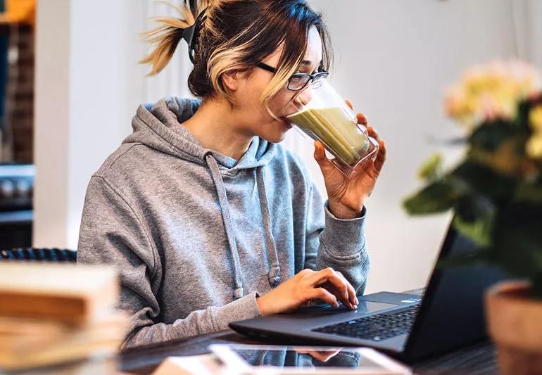woman drinks smoothie while working
