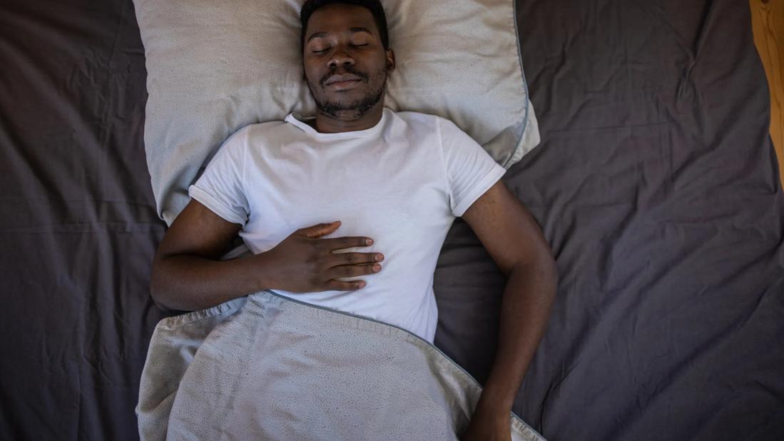 Person sleeping on their back with hand on chest