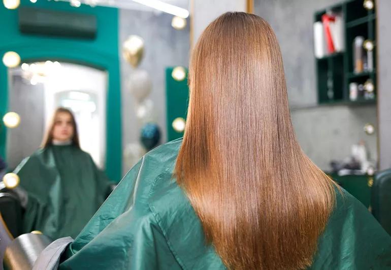 Client in chair at hair salon with long smooth brown hair after a keratin hair treatment.