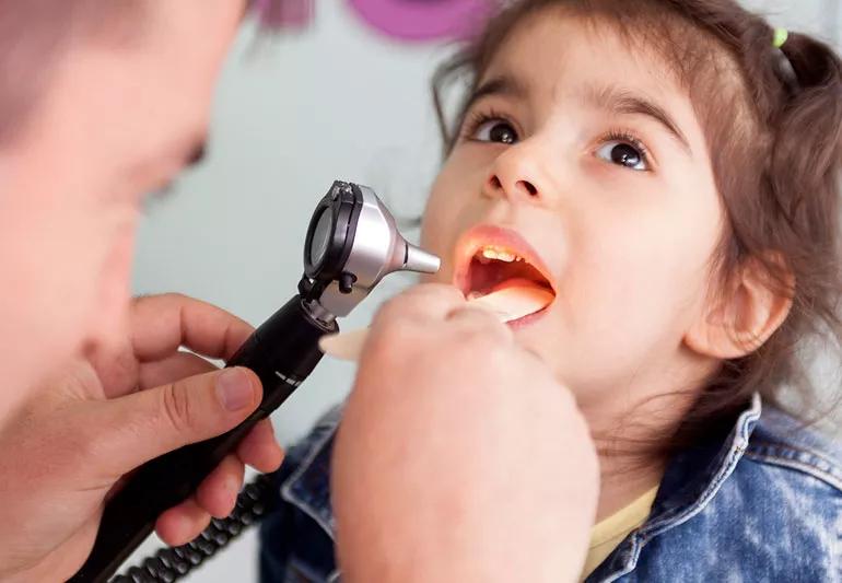 Doctor examines inside throat of little girl