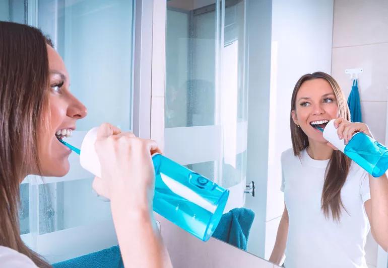 Person using water dental flosser in bathroom.