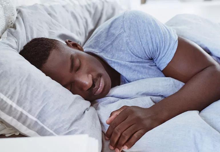 man sleeping restfully under blanket