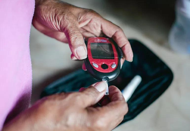 Person monitoring blood glucose level with glucometer.