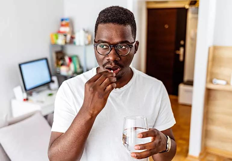 Male taking medication with water.