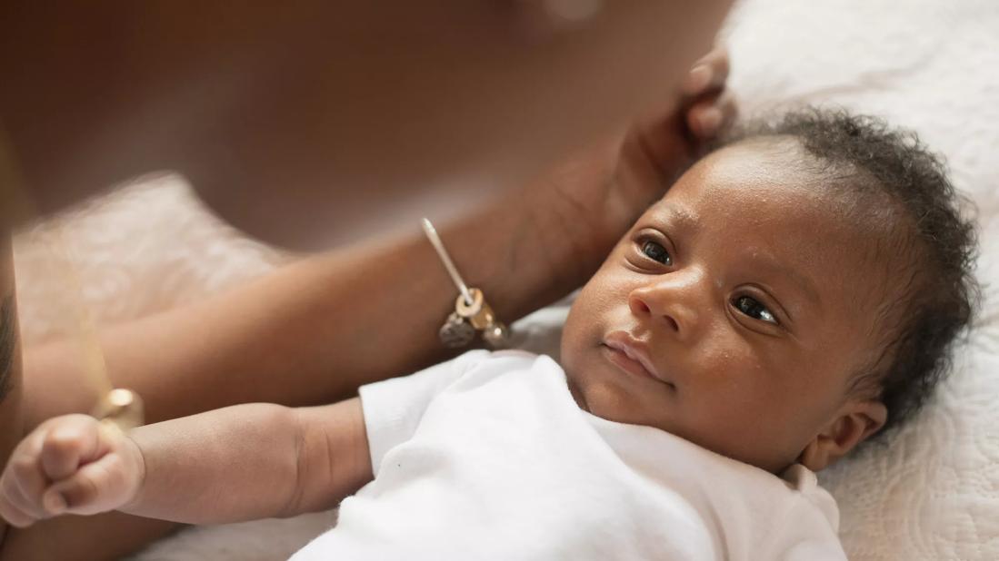 Caregiver leaning over happy baby