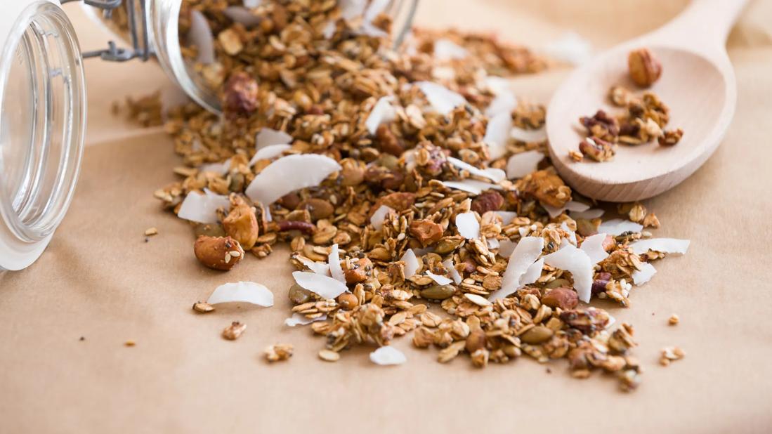 Almond and coconut trail mix poured from jar onto table