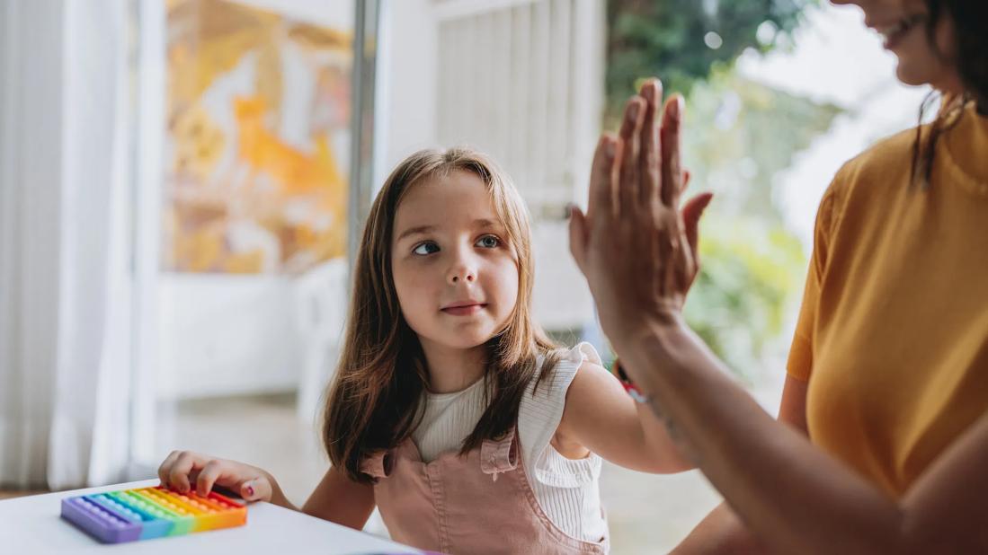 Child high-fiving parent as they play a game at a table