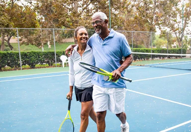 Active elderly couple exiting tennis court