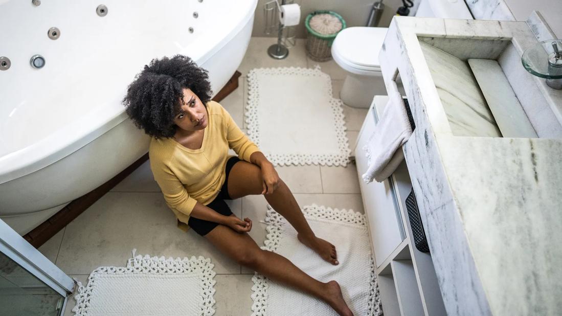 Female sitting on bathroom floor looking worried