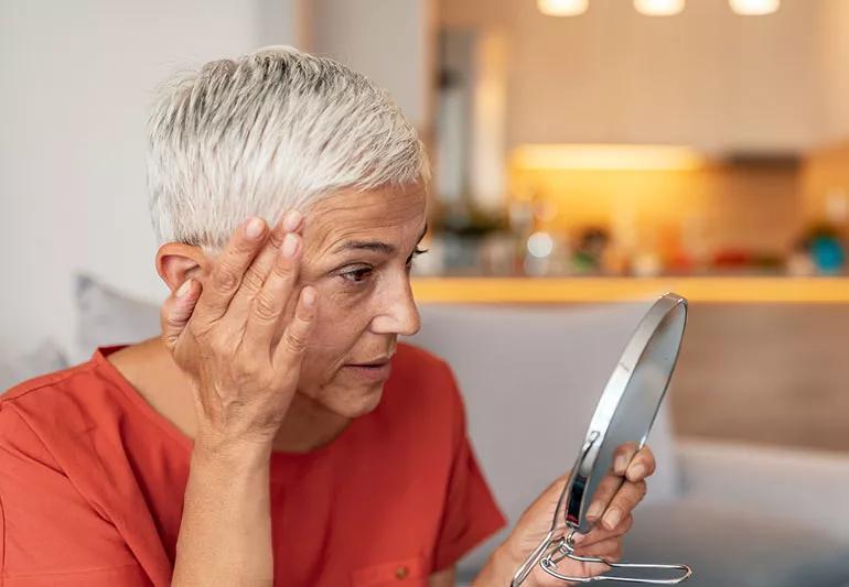 woman checking thinning hair in mirror